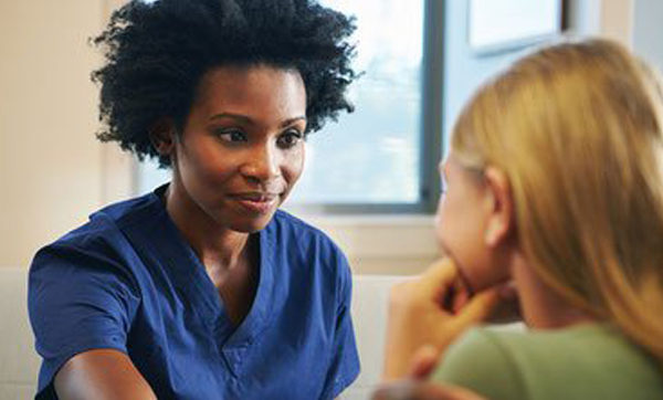 health professional in blue scrubs speaking with a patient