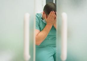 Sad man in scrubs holding his head