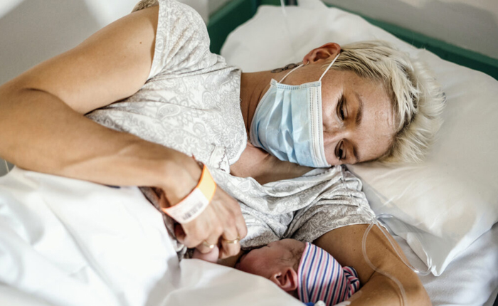 Photo of a mother in a hospital bed breastfeeding her newborn baby