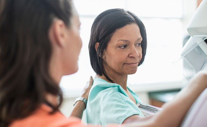 A woman having a mammogram with a nurse nearby