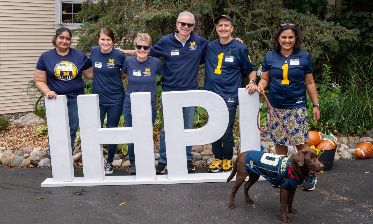 IHPI staff and members standing behind large "IHPI" letters