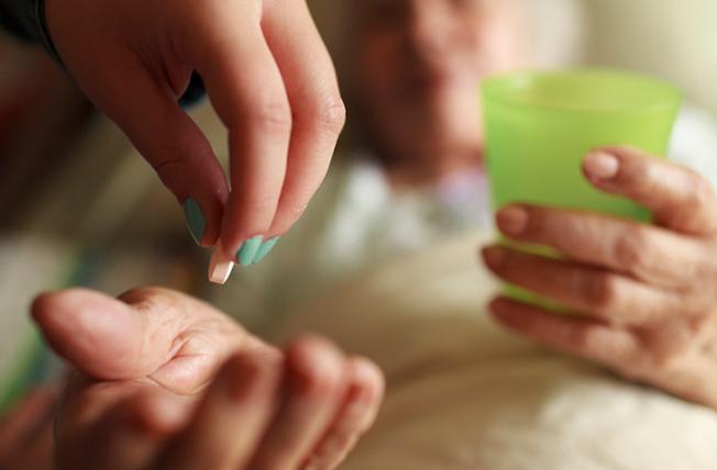 Woman being handed a pill in bed