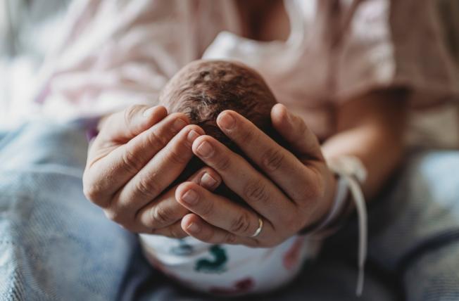Mother's hands cradling newborn baby's head