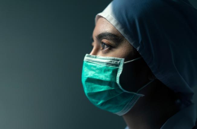 A masked surgeon woman looking somber