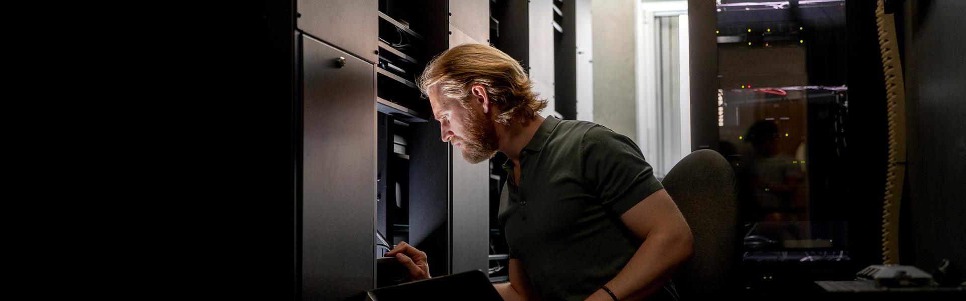 man looking at an unseen computer screen in a data center