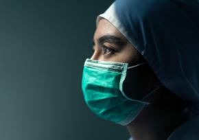 A masked surgeon woman looking somber